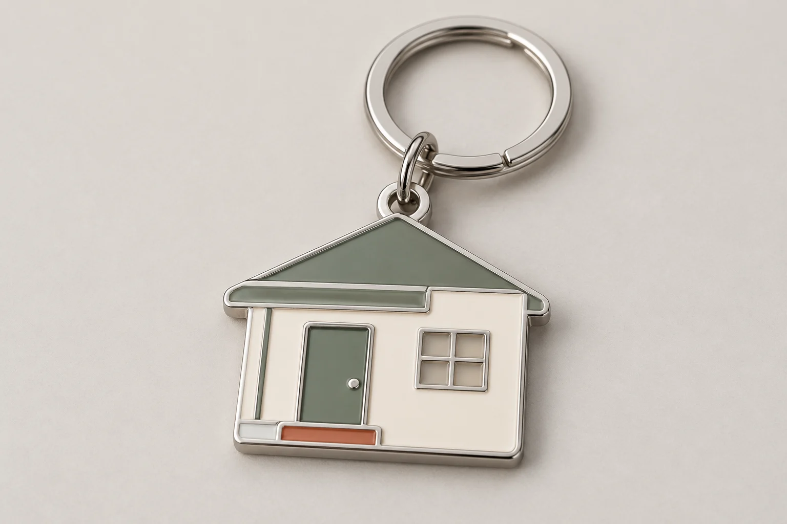 House-shaped metal keyring with cream walls, a sage-green door, terracotta steps and a silver ring